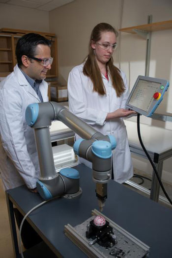 Facundo Fernandez (left) and Rachel Bennett, use a robotic arm to probe objects with irregularly-shaped surfaces for mass spectrometry