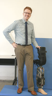 Dr. Robert Gregg stands next to a robotic leg