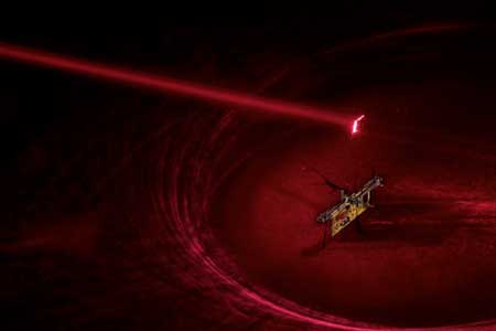 To power RoboFly, the engineers pointed an invisible laser beam (shown here in red laser) at a photovoltaic cell, which is attached above the robot and converts the laser light into electricity