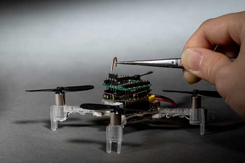 A drone with an antenna being attached with tweezers