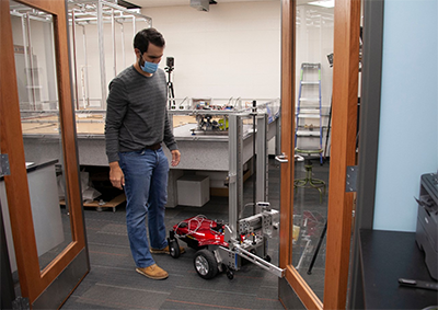 Engineering student Sam King demonstrates how an autonomous robot pivots around a door