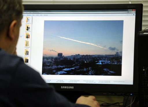 man looks at compter screen showing meteorite trail