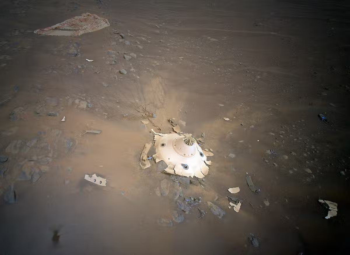 A smashed, round, white metal object on the surface of Mars