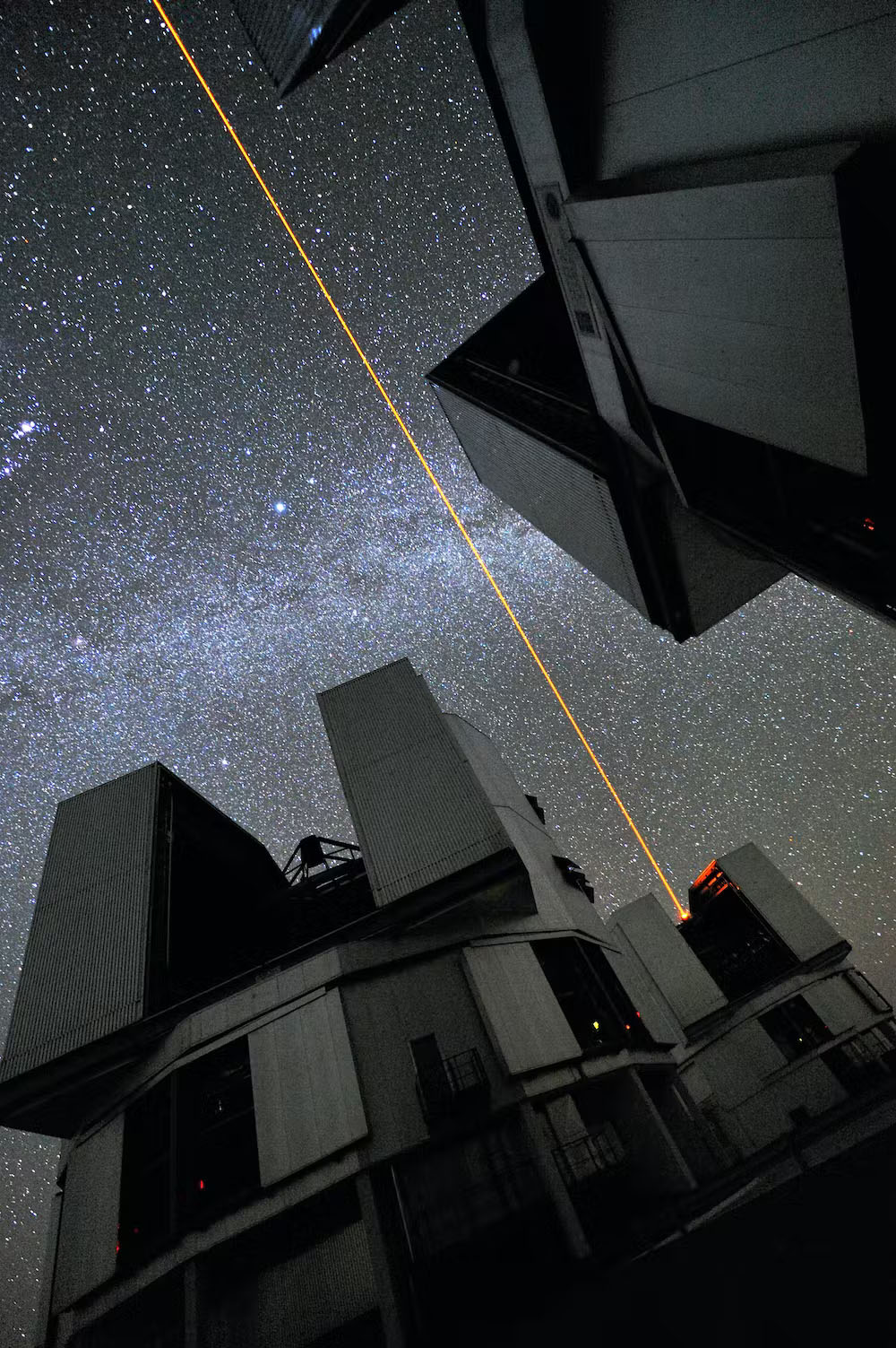 A laser shooting up from an observatory into a starry sky
