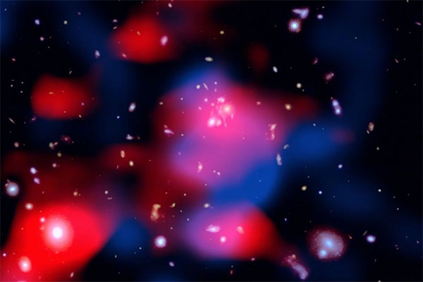 image reveals a distant galaxy cluster teeming with energy: galaxies shine in visible light (white), ghostly red clouds unveil a newly discovered radio mini-halo—the most distant ever detected—and blue wisps trace the hot gas glowing in X-rays