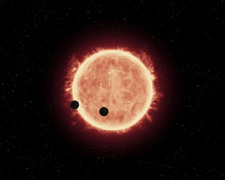 This artist's impression shows two Earth-sized worlds passing in front of their parent red dwarf star in the TRAPPIST-1 system