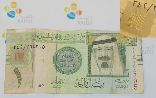 Photograph of a 1-Saudi Riyal note covered with arrays of polymer ferroelectric memory devices